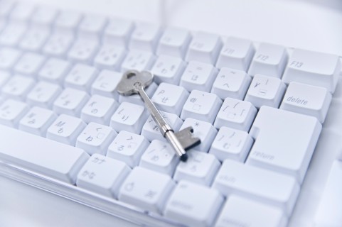 パソコンの白いキーボードにと銀色の南京錠の大き目の鍵が乗っています。